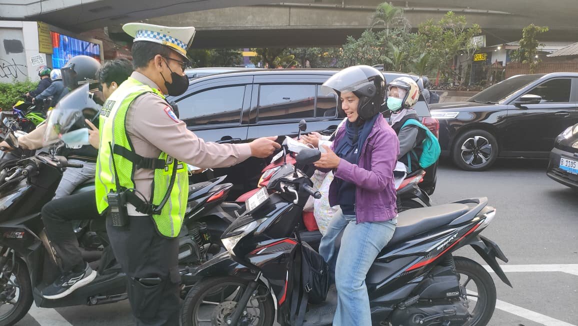 Personel Satlantas Jakarta Barat membagikan masker kepada pengguna jalan